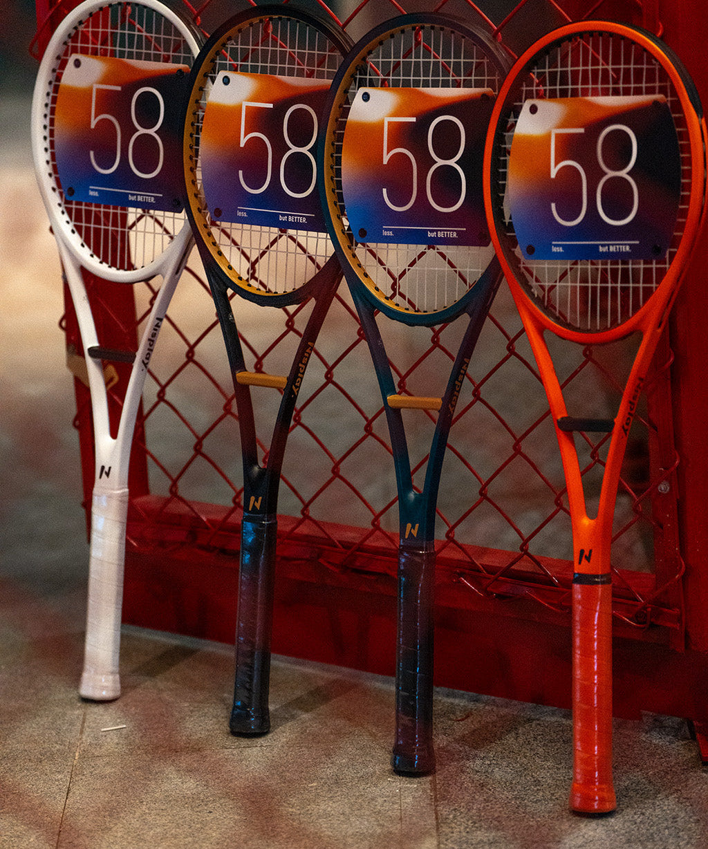 Four Nisplay 58 Sweet Spot Trainers in different colors beside a tennis court fence